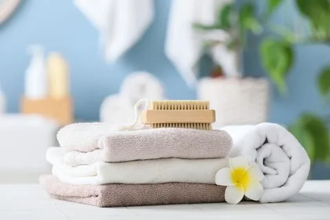 Stack of soft towels with bath brush and flower in spa setting Stock Photos