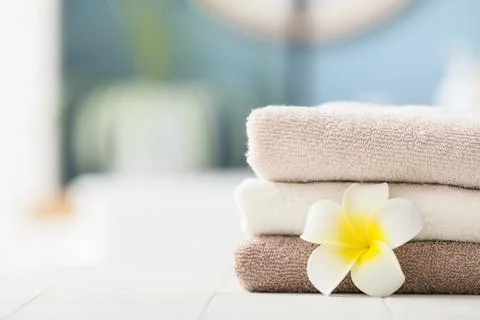 Stack of soft towels with plumeria flower on white surface Stock Photos
