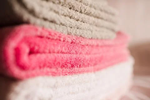 Stack of soft towels staying in bed in hotel room close up. Selective focus. Stock Photos