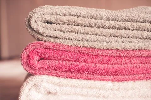 Stack of soft towels staying in bed in hotel room close up. Selective focus. Stock Photos