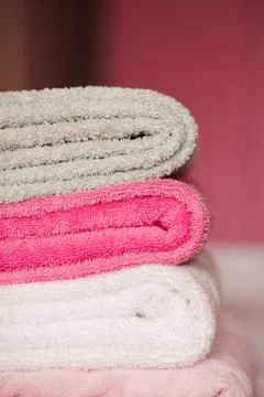 Stack of soft towels staying in bed in hotel room close up. Selective focus. Stock Photos