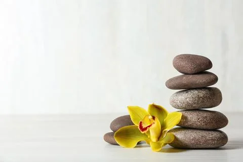 Stack of spa stones and flower on table against white background, space for t Foto stock