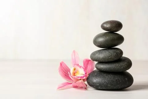 Stack of spa stones and flower on table against white background, space for t 스톡 사진