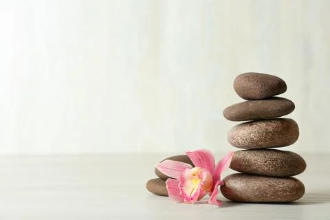 Stack of spa stones and flower on table against white background, space for t 스톡 사진