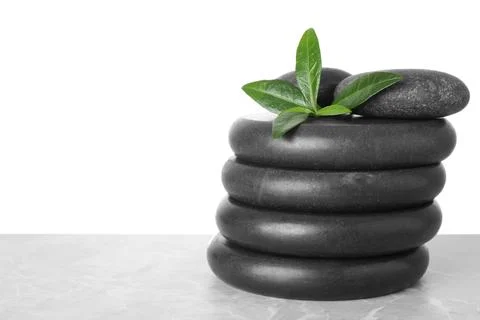 Stack of spa stones and green leaves on table against white background. Space 写真素材