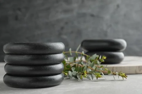 Stack of spa stones and green leaves on grey table, space for text 스톡 사진