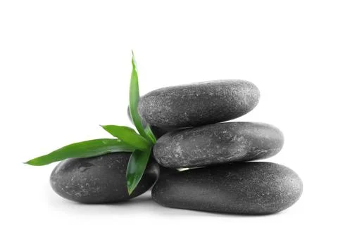 Stack of spa stones and leaves with water drops on white background Stockfoto's