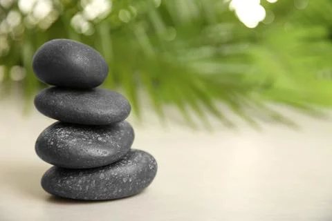 Stack of spa stones on table against blurred background. Space for text Foto stock