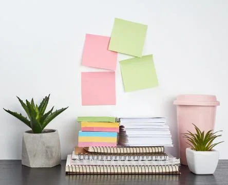 Stack of spiral notebooks and colored stickers, next to a ceramic pot with a  스톡 사진