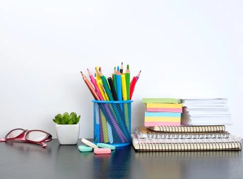 Stack of spiral notebooks and colored stickers, next to a ceramic pot with a  Stock Photos