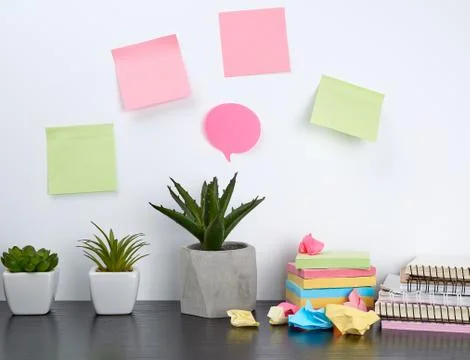 Stack of spiral notebooks and colored stickers, next to a ceramic pot with a  스톡 사진