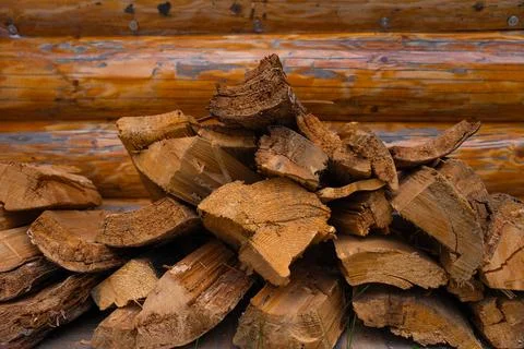 Stack of split firewood in front of wooden cabin wall - natural fuel storage for Stock Photos