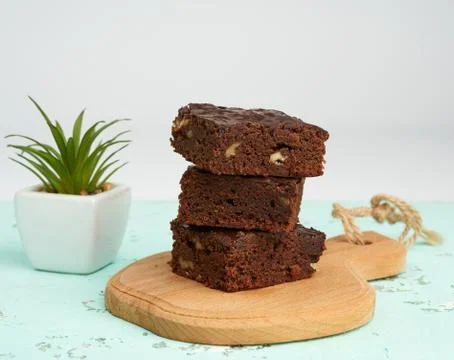 Stack of square baked slices of brownie chocolate cake with walnuts on a wood Stock Photos