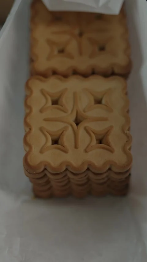 Stack of square butter cookies with wavy edges in white paper Stock Footage 332976363