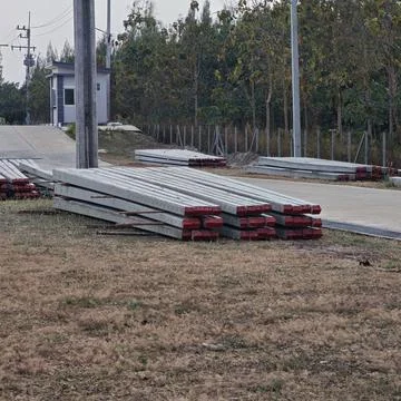 Stack of square concrete electrical power poles lying on ground. Stock Photos