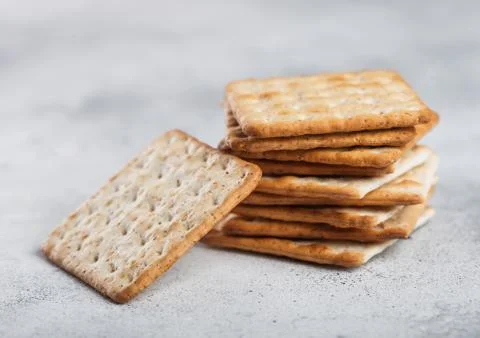 Stack of square organic crispy and salty crackers on light kitchen table Stock Photos