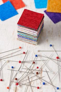 Stack of square pieces of colorful fabrics and heap of multicolor ball head.. Stock Photos