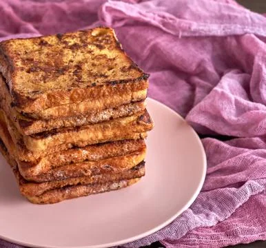 Stack of square pieces of fried bread slices on a pink ceramic round plate Foto stock