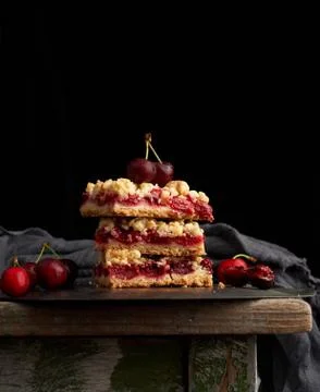 Stack of square slices of a pie with red cherry, black background Foto stock