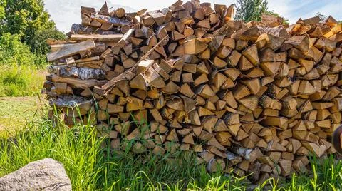 Stack of stacked firewood on a summer blue sky background Stock Photos