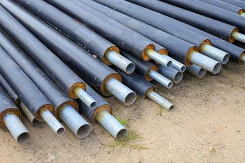 Stack of steel heating pipes resting on ground. Utility modernizing, heatin.. Фото