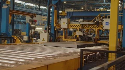 A stack of steel plates on a roller bench are being bound together by a large Stock Footage 308210014