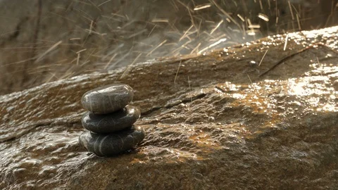 Stack of stones balancing on wet surface on a background of splashing waterfall Stock Footage 128499764