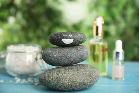 Stack of stones with drawn happy face light blue wooden table outdoors. Be in Stockfoto's