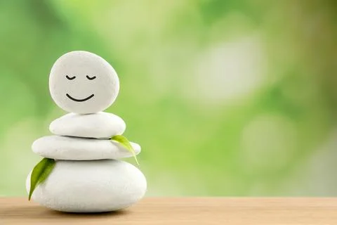 Stack of stones with drawn happy face and leaves on wooden table, space for t Stockfoto's