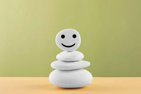 Stack of stones with drawn happy face on beige table against light green ba.. 스톡 사진