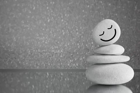 Stack of stones with drawn happy face on grey background, space for text. Z.. 写真素材