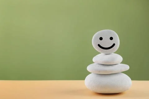 Stack of stones with drawn happy face on beige table against light green ba.. Stockfoto's