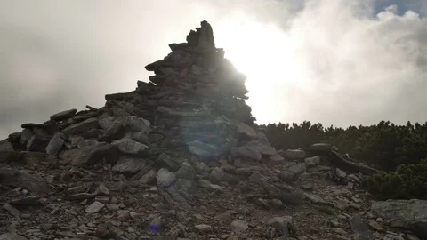 Stack of stones on mountain top on background of rapidly running clouds on Stock Footage 77572214