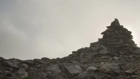 Stack of stones on mountain top on background of rapidly running clouds on Stock Footage 77572599