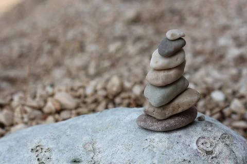 A stack of stones pebbles balance on a large stone Stock Photos