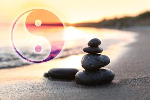Stack of stones on sandy beach and Ying Yang symbol. Feng Shui philosophy Stock Photos