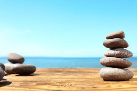 Stack of stones on wooden table against seascape, space for text. Zen concept Foto stock