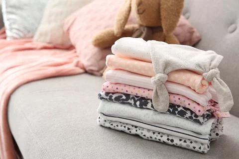 Stack of stylish child clothes on sofa 스톡 사진