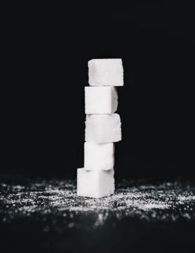 Stack of sugar cubes, balancing one on top the other, on black backdrop Stockfoto's