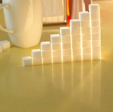 Stack of sugar cubes in the shape of a graph on a yellow table 스톡 사진