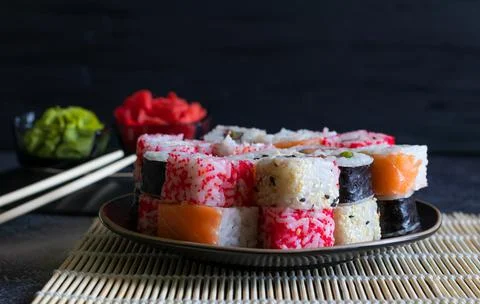 Stack of sushi rolls with wasabi and ginger on black plate and dark backgroun Stock Photos