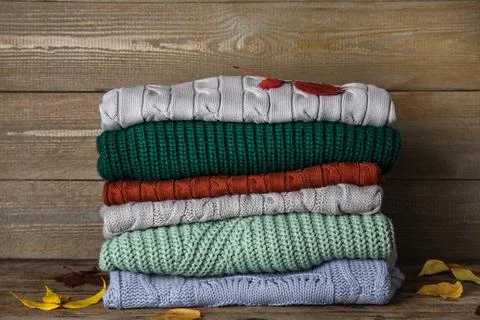 Stack of sweaters on wooden background. Autumn clothes 스톡 사진
