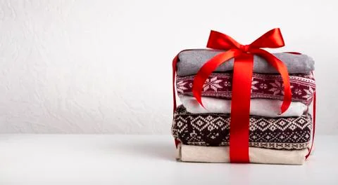 Stack of sweaters wrapped by red ribbon with bow on white Stock Photos