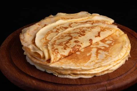 A stack of sweet homemade thin pancakes (crepes) on a brown wooden board Stock Photos