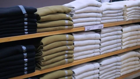 Stack T-shirts different colors and sizes on shelf in department store. Buyers Stock Footage 257325077