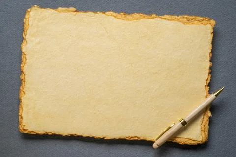 Stack of tan toned heavyweight deckle edge paper sheets with a stylish pen Stock Photos
