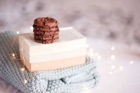Stack of tasty chocolate cookies on open books and knitted sweater over Chris Stock Photos