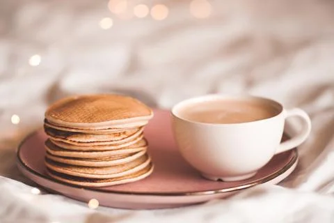 Stack of tasty pancakes with cup of coffee in bed closeup. Good morning. Brea Stock Photos