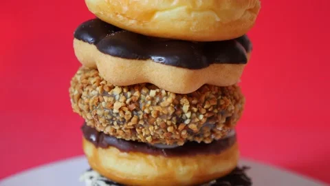 Stack of tasty sweet different colored donuts on red background Video stock 148622727