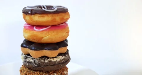 Stack of tasty sweet different colored donuts on white background Stock Footage 148622887